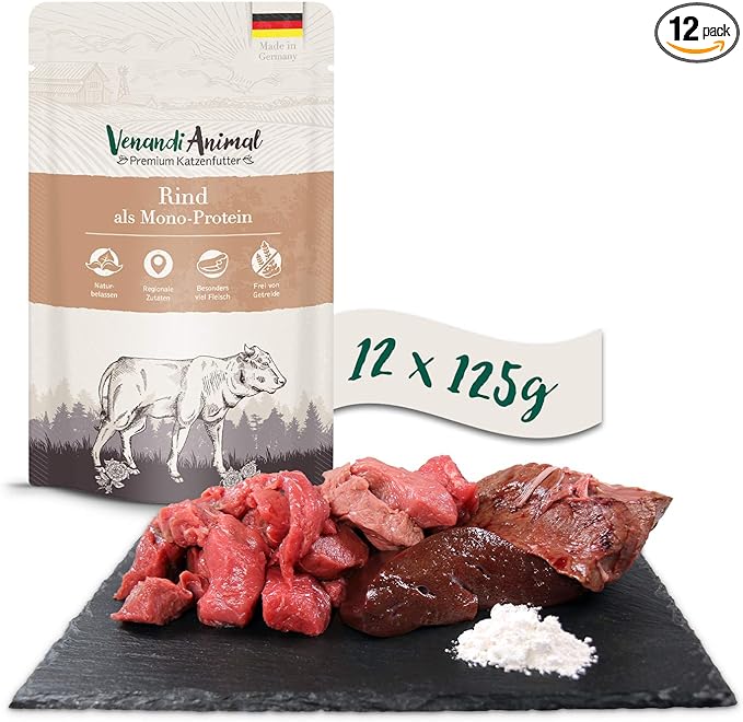 Eine Packung Venandi Animal Premium, fleischreiches Katzenfutter mit Rindfleisch als einziger Proteinquelle wird ausgestellt. Um die Packung herum sind auf einer schwarzen Tafel Stücke rohen Rindfleischs, ein Stück roher Leber und ein kleiner Haufen weißen Pulvers. Der Text lautet „12 x 125 g“.